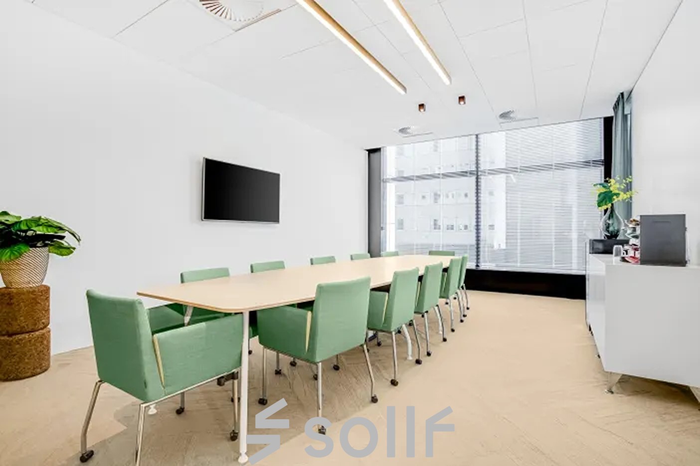 Modern eingerichtetes Büro mit großem Konferenztisch und grünen Stühlen in der Brückenkopfgasse 1, ideal für Teams auf der Suche nach einem Büroraum mieten in Graz.
