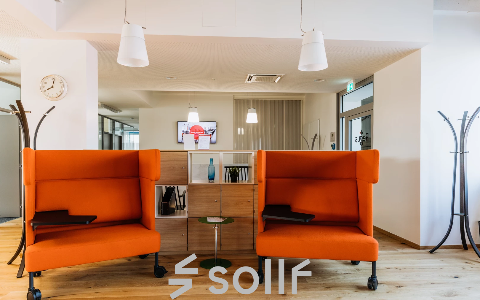 Moderne und einladende Büroecke mit orangefarbenen Sofas und einer stilvollen Beleuchtung in der Waagner-Biro-Straße 47, perfekt um einen Büroraum zu mieten.