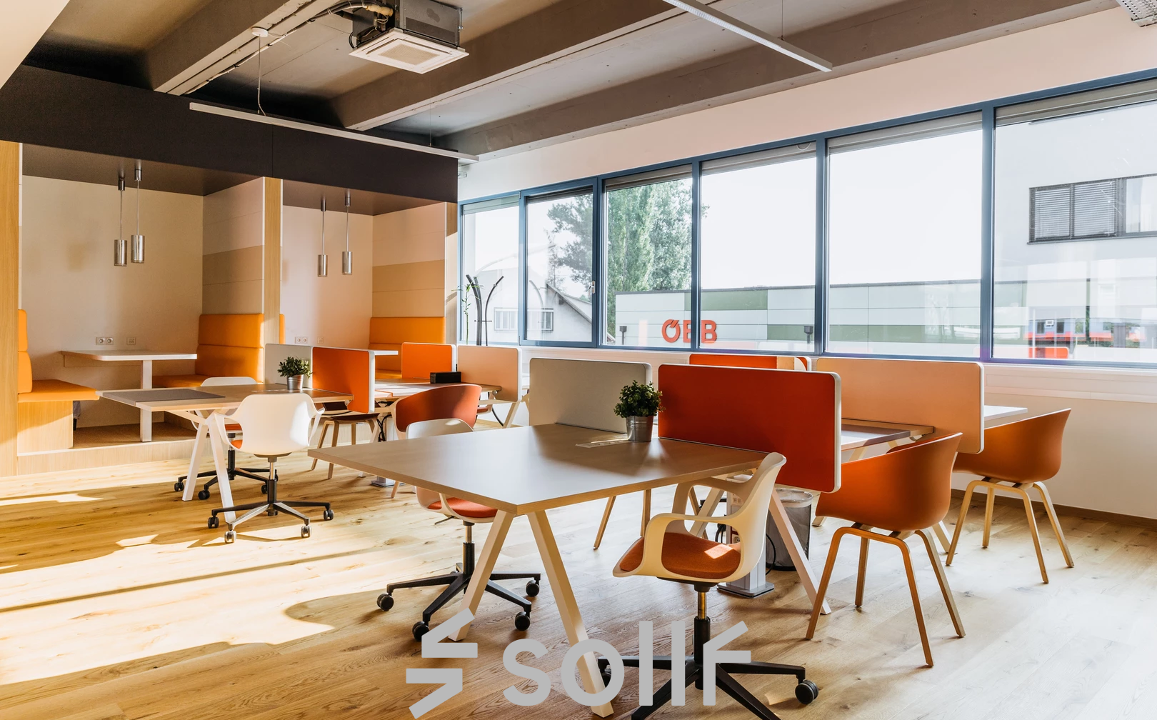 Modern gestalteter Büroraum mieten in Graz, Waagner-Biro-Straße 47, mit Holzboden, Schreibtischen und orangen Stühlen.