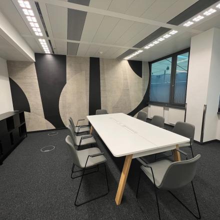 Modern office space rental at Am Euro Platz 2, 1120 Vienna Meidling, with a sleek white table, comfortable chairs, and stylish geometric wall design.
